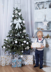 可爱的孩子在圣诞树附近拿着礼品盒