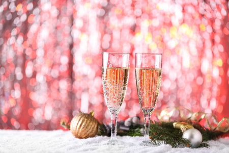 香槟杯和圣诞节装饰在雪地上，灯光模糊