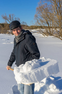 英俊的中年白种人清理家庭地块上的雪