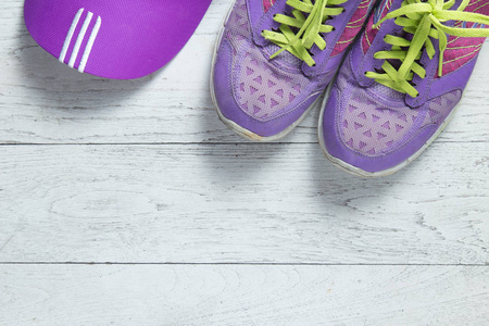 运动平躺紫色的鞋子和帽子在白色的木制背景与共空间为您的文本。 概念健康的生活方式和饮食。