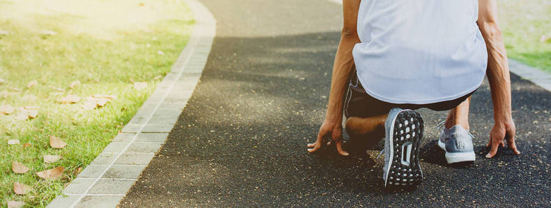 运动员在跑步时开始在公共公园的步行道上摆姿势。 健康生活和饮食观念。 横幅大小与复制空间。