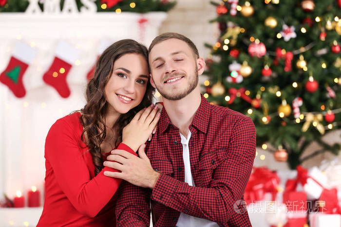 幸福的年轻夫妇坐在家中圣诞树旁