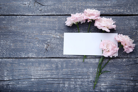 灰色的木桌上放着一张白纸的粉红色花