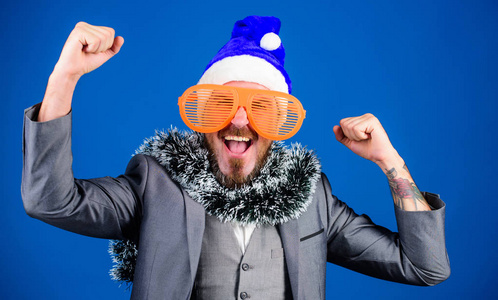 企业圣诞晚会男人留胡子的嬉皮士戴着圣诞老人的帽子和滑稽的太阳镜。金塞尔经理准备庆祝新年。企业假日派对的想法员工会喜欢的。圣诞晚会