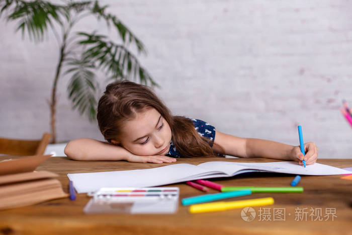 受启发的小女孩在桌子上画蜡笔或做家务