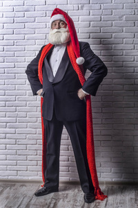 一个头发花白的胡须男子穿着黑色西装, 在圣诞老人的形象