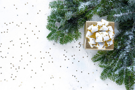 白雪覆盖的圣诞树树枝上放着圣诞礼物金色丝带和小金星星。 顶部视图