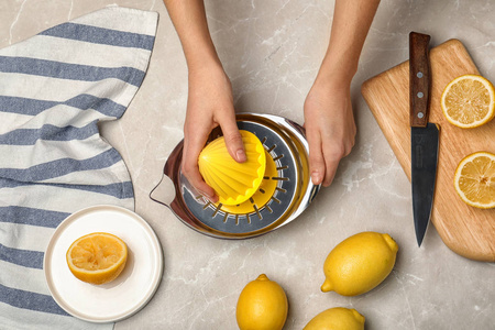 女人用榨汁机在桌面上捏柠檬图片