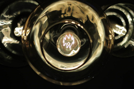 经典爱迪生灯泡在一个透明的玻璃天花板上的黑色背景