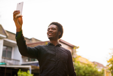 年轻英俊的非洲男人在户外使用手机