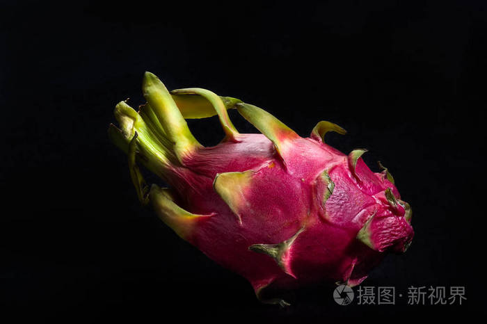 一个完整的未切割的火龙果孤立在黑色背景上