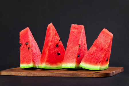 三角立体木板四个三角形的西瓜楔子放在黑色的木板上照片