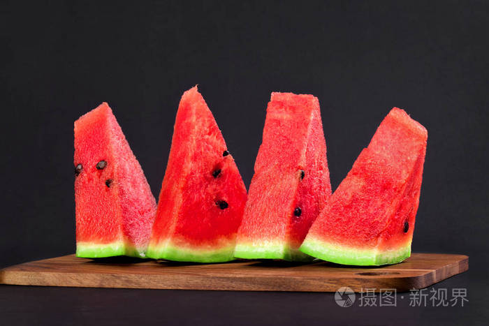 四个三角形的西瓜楔子放在黑色的木板上照片-正版商用图片14wahb-摄图