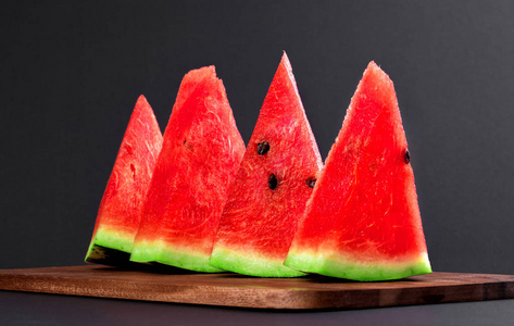 楔子隔离四个三角形的西瓜楔子放在黑色的木板上照片