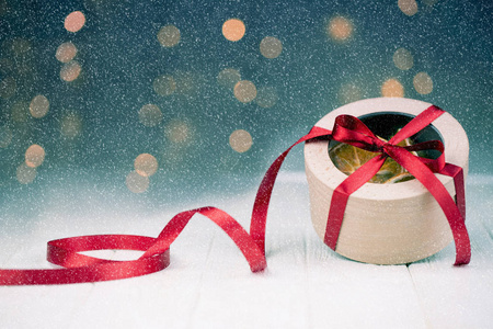 新年或圣诞礼品盒与红色丝带。雪落效果。