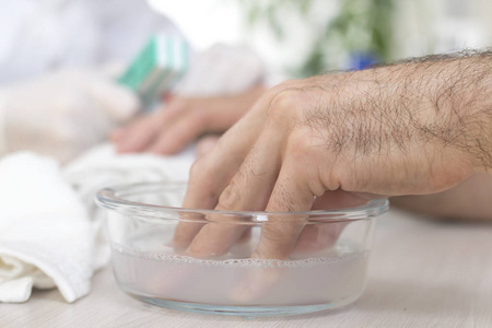 修指甲的男人在美容院,男人的手浸在一碗水里.准备修指甲.照片