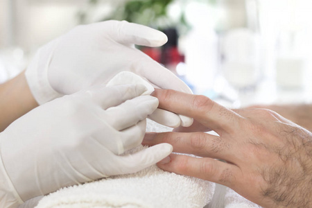 s hand during manicure in a beauty salon. Wiping the nails with 