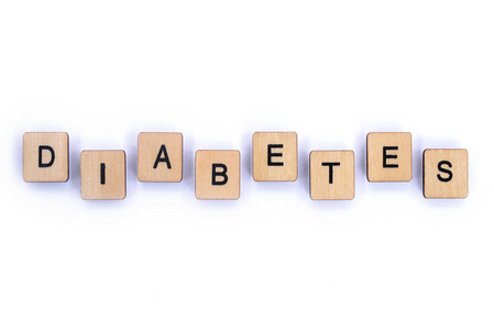 糖尿病这个词在一个普通的白色背景上用木制字母瓷砖拼写。