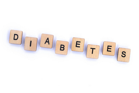 糖尿病这个词在一个普通的白色背景上用木制字母瓷砖拼写。