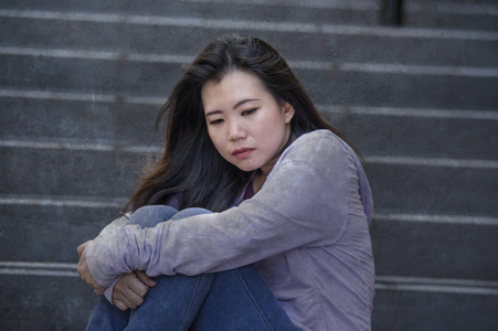 妇女或被欺负的青少年坐在户外的街道楼梯上,不知所措,焦虑地感到绝望