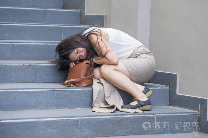 年轻的沮丧和绝望的亚洲韩国商界女性独自哭泣坐在街道