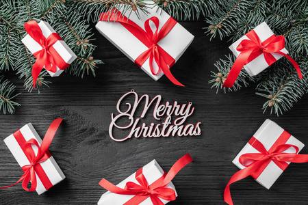 圣诞贺卡与白色的礼物和冷杉树枝在一个黑暗的木质质朴的背景, 文本的地方。圣诞节和快乐的新年贺卡。顶视图, 平面布局