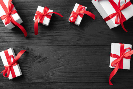 圣诞框架从节日礼物与红色丝带在黑暗的木制背景。圣诞节和快乐的新年卡。顶部视图, 平面布局, 复制空间