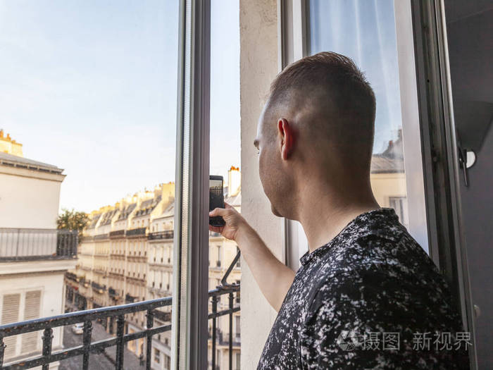 巴黎，法国，十月二十三日，2018年。年轻人在智能手机上拍摄窗外的风景
