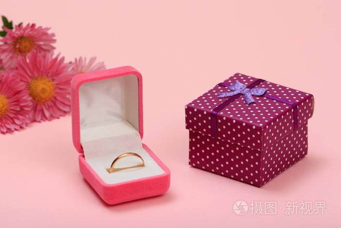 金色戒指在盒子礼盒和花在粉红色的背景上女性珠宝和配饰