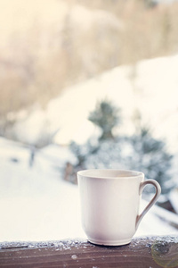 杯子上有咖啡茶的背景冬季景观。 在冬天森林的背景上喝热饮料的杯子。 冬天的桌子在户外。 冬季时间概念。