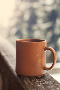 杯子上有咖啡茶的背景冬季景观。 在冬天森林的背景上喝热饮料的杯子。 冬天的桌子在户外。 冬季时间概念。