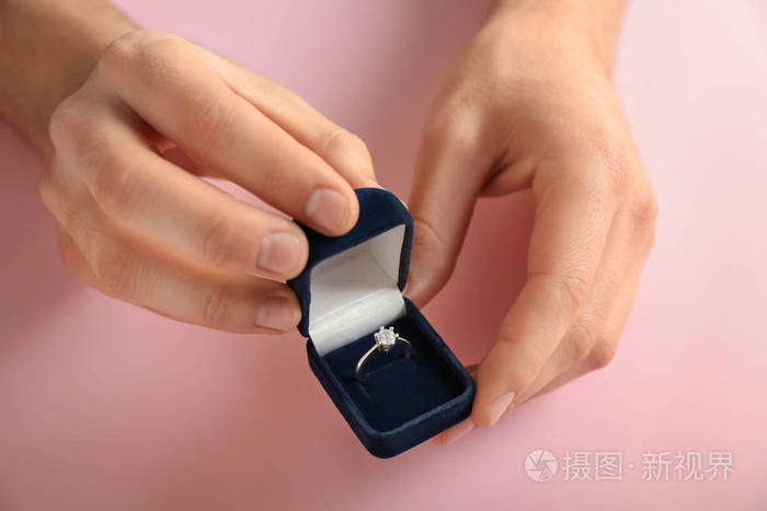 男性手拿盒子,带订婚戒指,颜色背景
