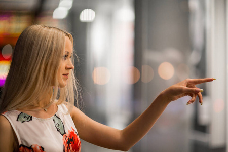 垫高点橱窗美丽的女孩在夜城街的商店橱窗里看着照片