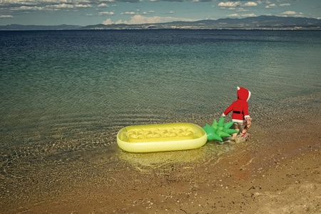 圣诞快乐儿童圣诞老人与菠萝床垫在海滩水