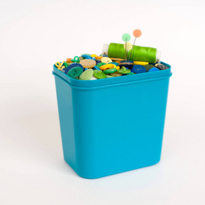 一种塑料桶,在白色背景上隔离了各种五颜六色的纽扣.照片