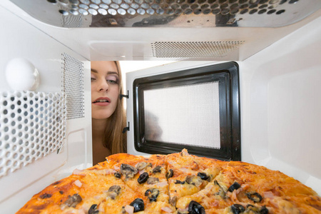 在微波炉里看披萨的女孩图片