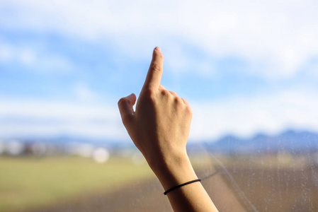 s hands touching window, seeking ideas. Daylight landscape on ba