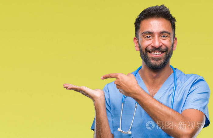 成年西班牙裔医生或外科医生，在孤立的背景惊讶和微笑的相机，同时呈现手和手指。
