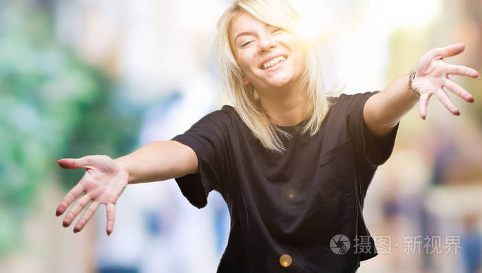 年轻漂亮的金发女人在孤立的背景下,看着相机,张开双臂拥抱微笑.