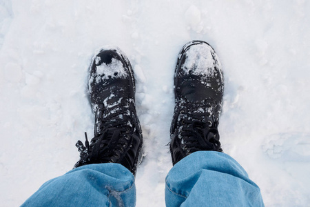 双脚穿着黑色的长途跋涉的靴子在雪地上旅行，冬天的旅行，上面的照片。