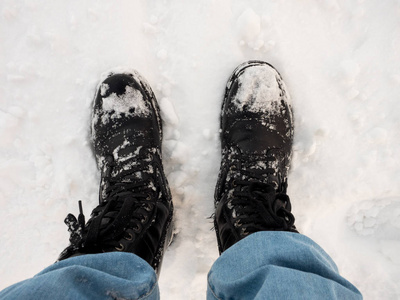双脚穿着黑色的长途跋涉的靴子在雪地上旅行，冬天的旅行，上面的照片。