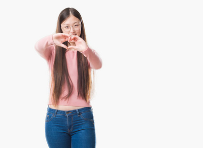 年轻的中国女人在孤立的背景上戴着眼镜，微笑着，爱着，用手显示出心脏的象征和形状。 浪漫的概念。