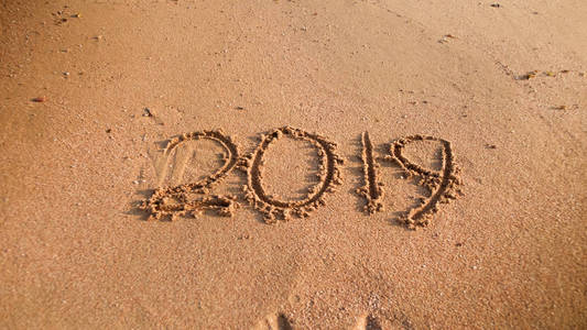 在海滩上的湿沙上写的2019年数字照片。寒假新年和旅游的概念