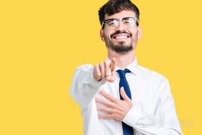 年轻英俊的商人戴戴着眼镜,在孤立的背景下笑着用手指指着相机,用手指