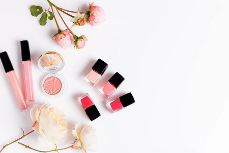 化妆产品与粉红色的英语上升在轻的背景。美丽平躺与化妆品瓶和花