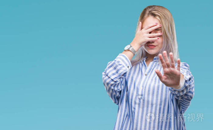 年轻的金发女人在孤立的背景上用手遮住眼睛,用悲伤和恐惧的表情做