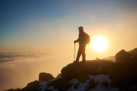 游客徒步旅行者背着背包和登山杖在落基山山顶上日落背景的后景摄影图