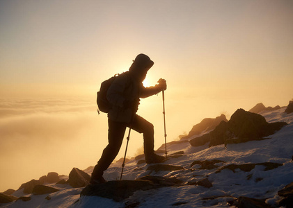 游客徒步旅行者背着背包和登山杖在落基山山顶上日落背景的后景摄影图