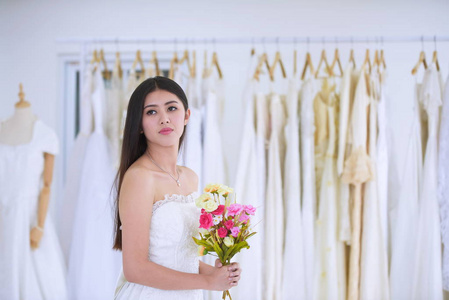 新娘和花束很高兴在更衣室里试穿婚纱，新娘来测量更衣室里新娘礼服的准备情况。