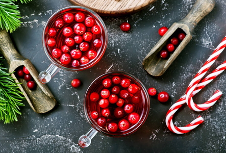 圣诞糖果罐和蔓越莓饮料的顶部视图与浆果在黑暗的桌面